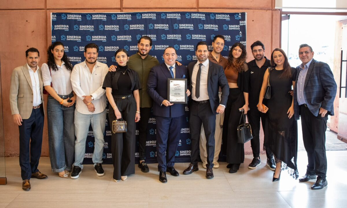Integrantes y asistentes de Reconoce Jalisco 2026 posan frente al panel de Sinergia Empresarial en Tequila Lab, Zapopan; al centro, un participante sostiene un reconocimiento.